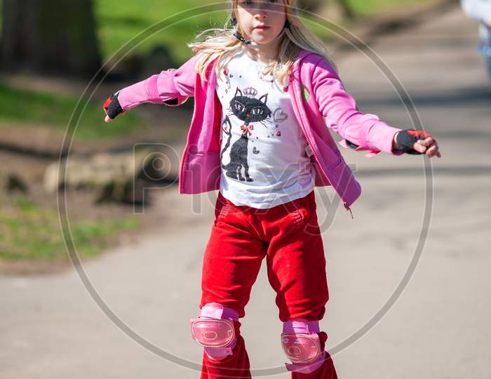 A Young Girl On Roller Blades Wearing Protective Equipment
