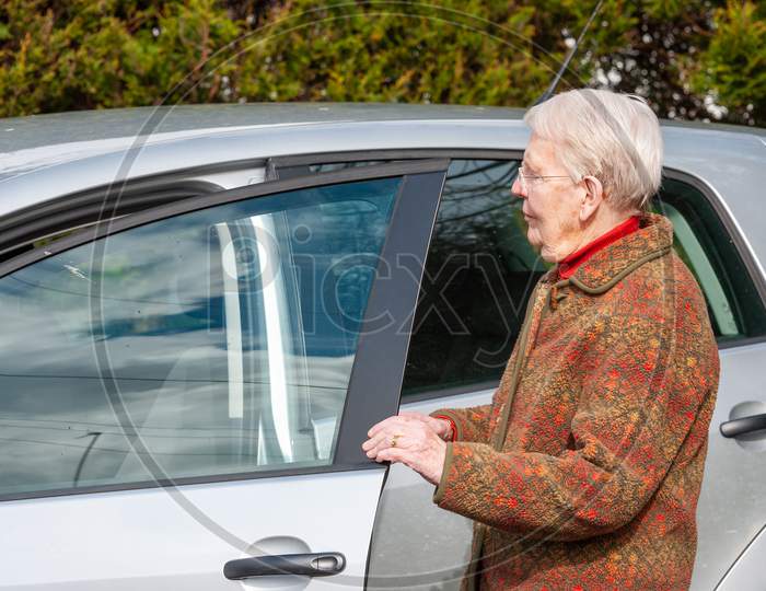 An Elderly Lady Opening A Car Door