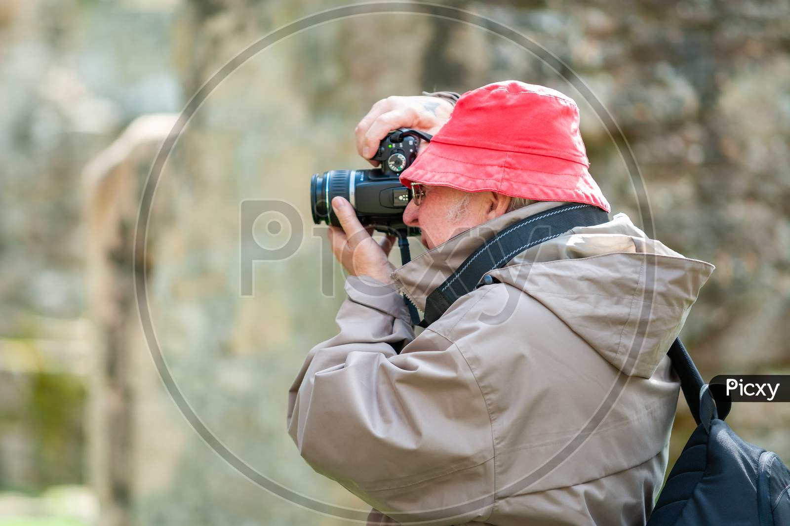 An Elderly Man Uses A Camera In Ancient Ruins