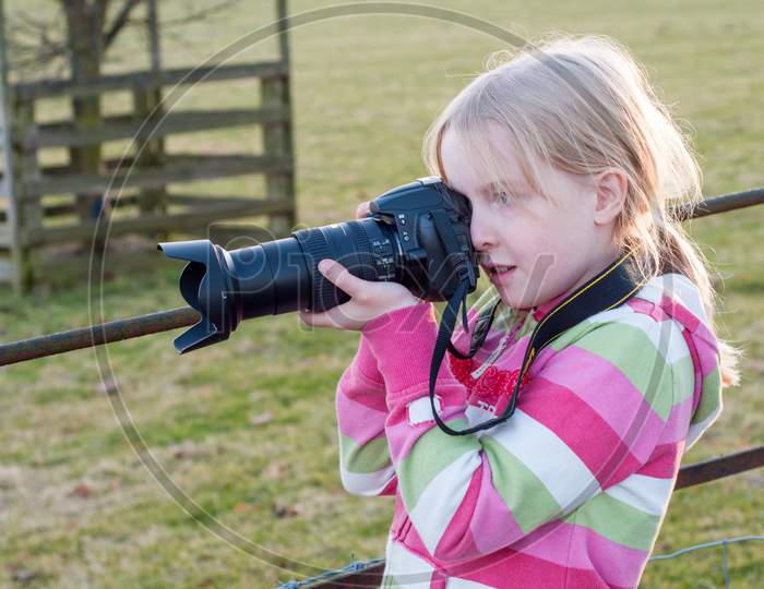 Young Blonde Girl Using A Camera With A Large Zoom Lens