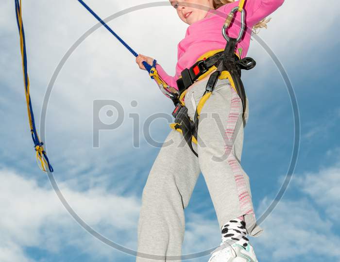 Happy Young Blonde Girl Bouncing While Attached To Bungee Cords