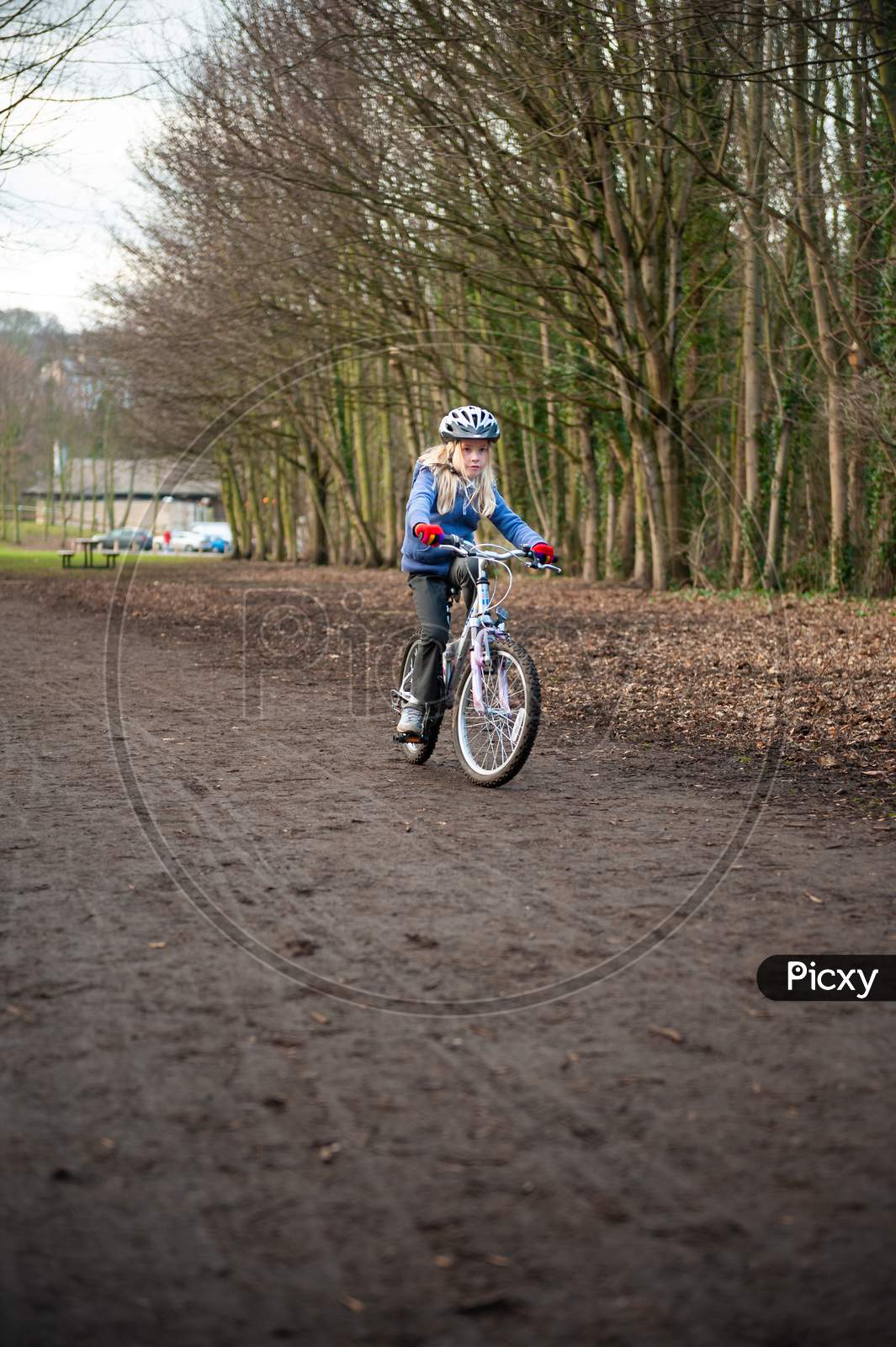 A Young Girl Riding A Bike Along A Country Track Towards The Camera.