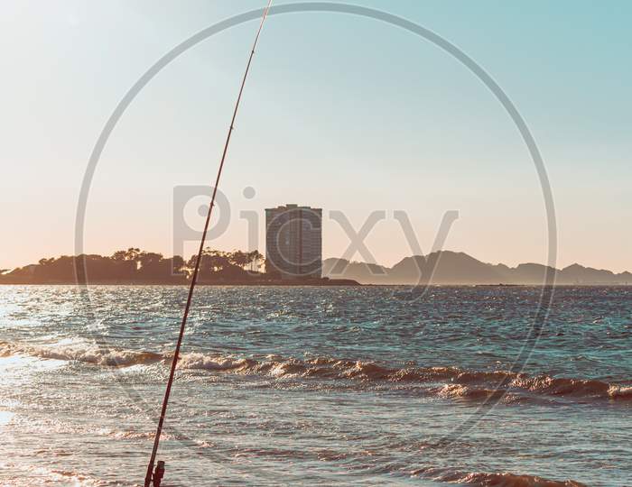 Fishing Rod In A Beach In Front Of A Massive Building During A Sunset In Spain