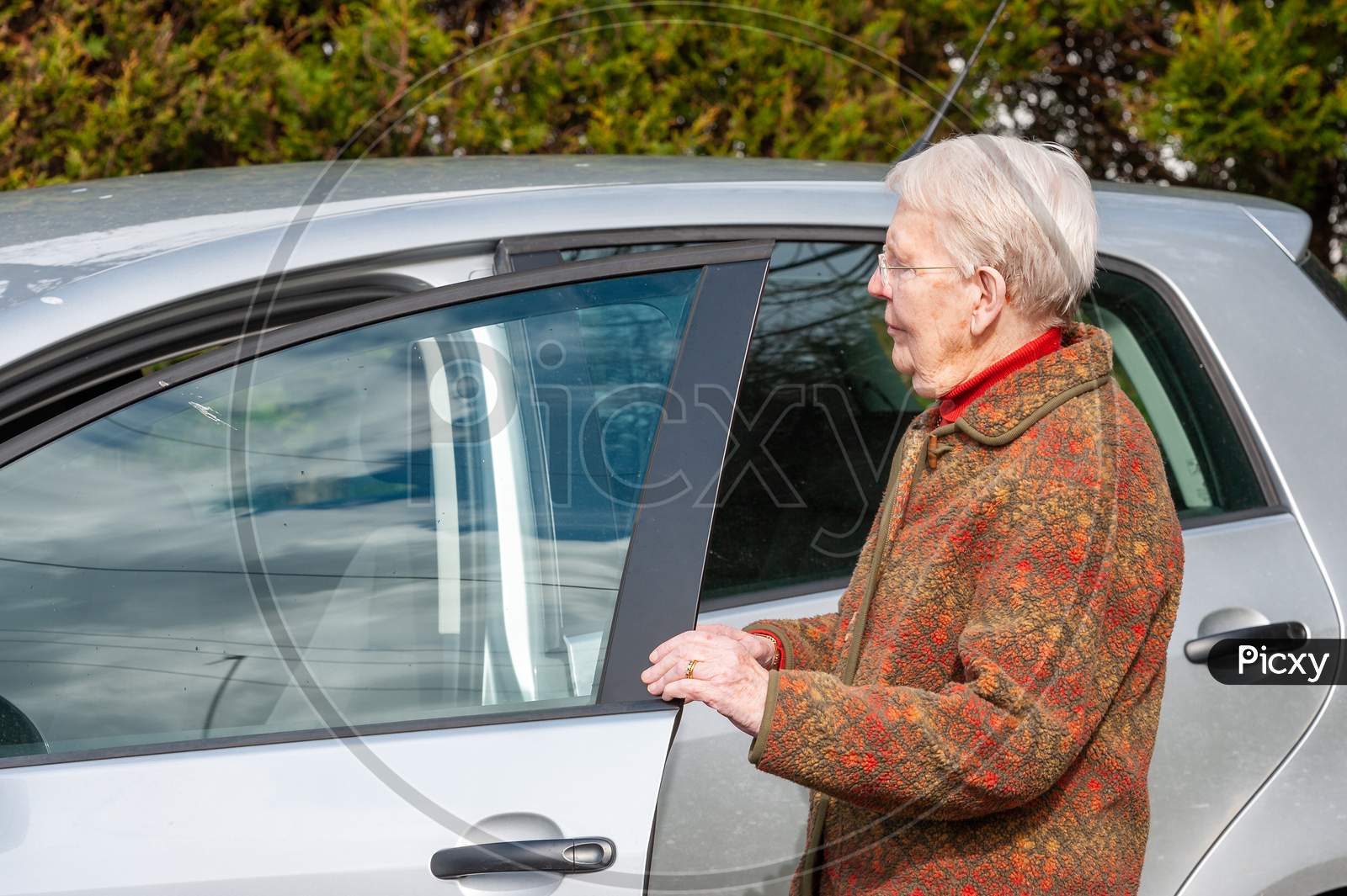 An Elderly Lady Opening A Car Door