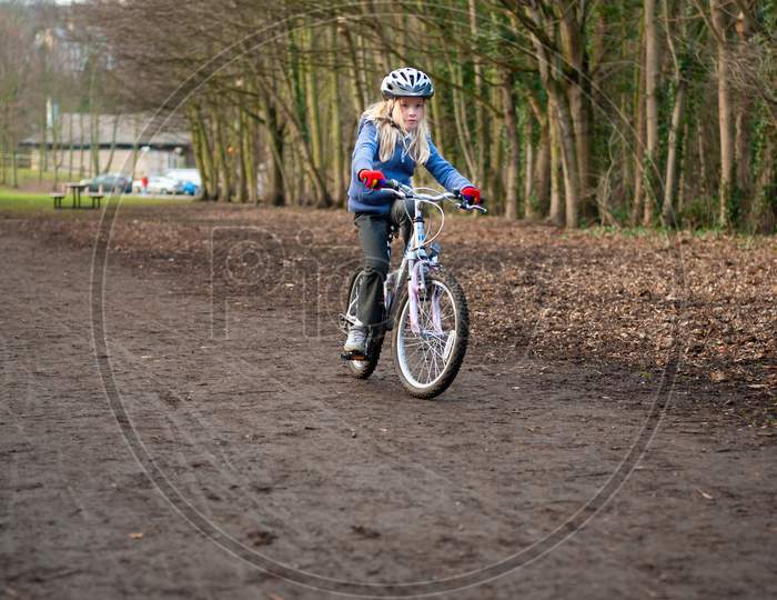 A Young Girl Riding A Bike Along A Country Track Towards The Camera.