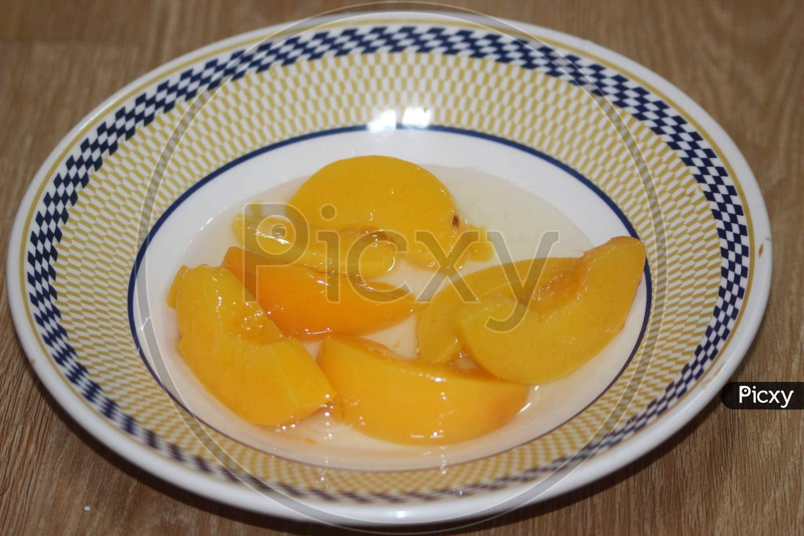 Canned Peaches Halves Sprinkled With Syrup In White Plate.