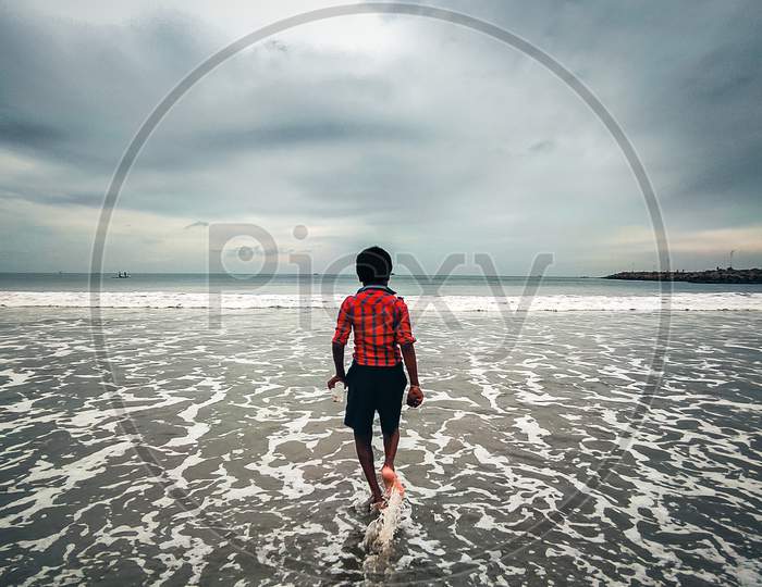 A boy with Red shirt walking in beach