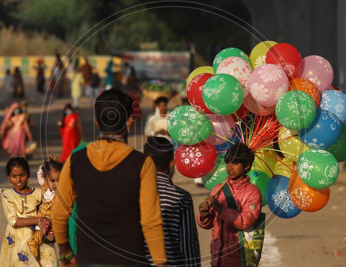 A Boy awaiting customer to sell colourful balloons near Chhath puja, Ghat in Ghaziabad , November 20, 2020..