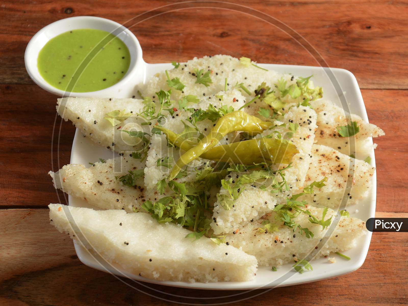 Khaman White Dhokla Made Up Of Rice Or Urad Dal Is A Popular Breakfast Or Snacks Recipe From Gujarat, India, Served With Green Chutney And Fried Chilli.. Selective Focus