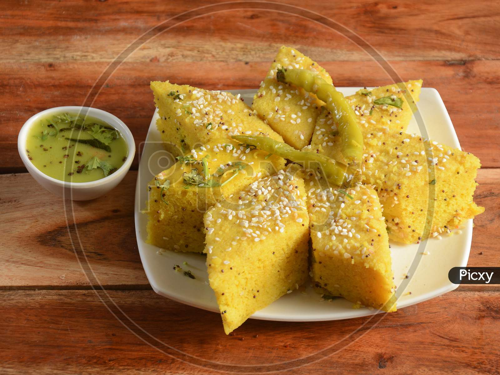 Khaman Dhokla Made Up Of Rice Or Urad Dal Is A Popular Breakfast Or Snacks Recipe From Gujarat, India, Served With Green Chutney And Fried Chilli.. Selective Focus