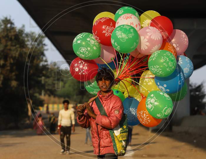 A Boy awaiting customers to sell colourful balloons near Chhath puja, Ghat in Ghaziabad , November 20, 2020..
