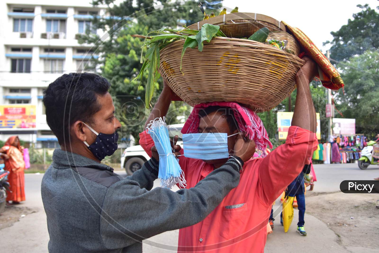 A member of puja committee help a devotee  to wear a mask on the occasion of Chhath Puja in Nagaon district, in the northeastern state of Assam on Nov 20,2020.