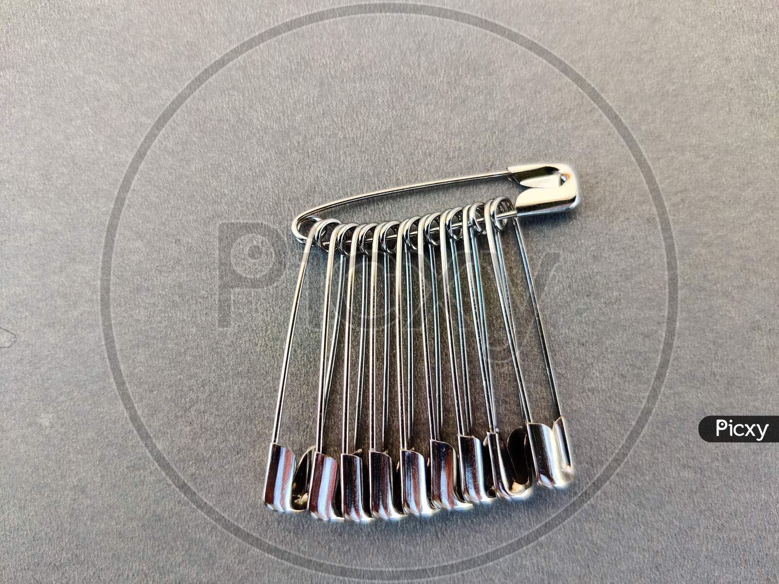 Set Of Safety Pins. Isolated On Grey Background.