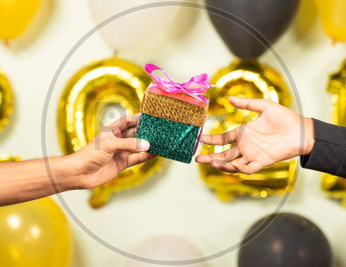Close Up Of Hands Giving Present Gift Box In 2021 New Year Celebration On Decorated Background - Concept Of Gift Sharing On New Year Holydays.