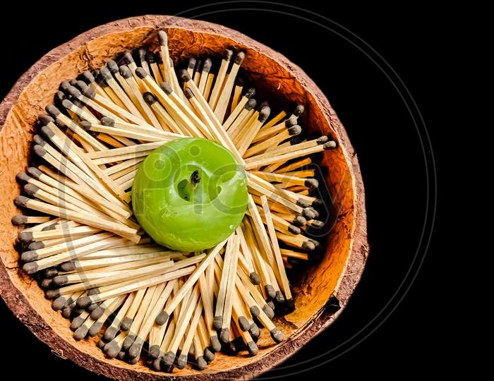 Candle and matchstick on coconut shell, isolated on black background.