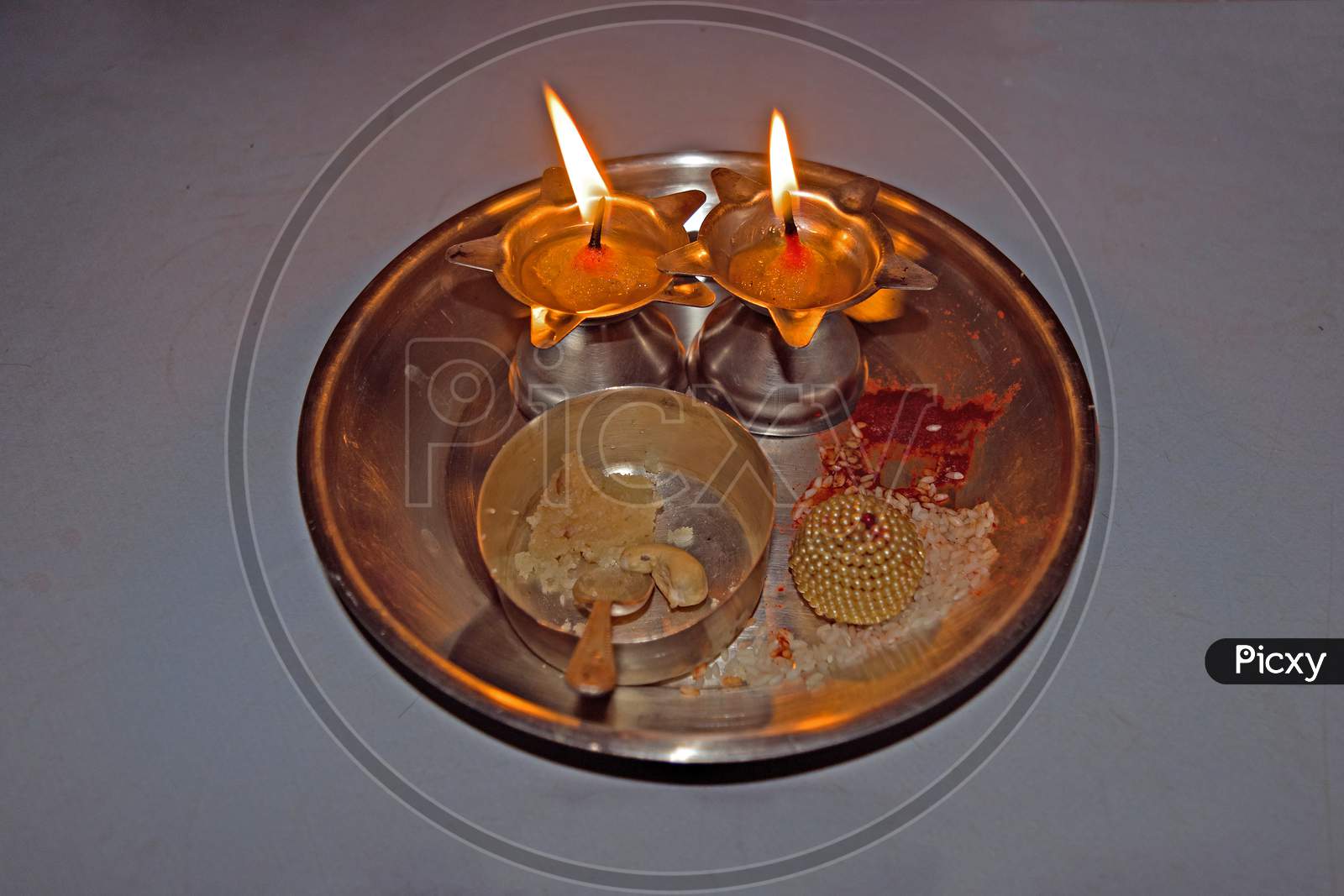 Isolated image of Indian Puja thali with two lit lamps.