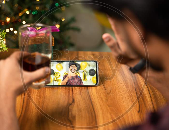 Shoulder Shot Of Young Man Partying During New Year Or Christmas Celebration Video Call On Mobile - Concept Of Distance Holyday Celebration Due To Coronavirus Or Covid-19 Pandemic.