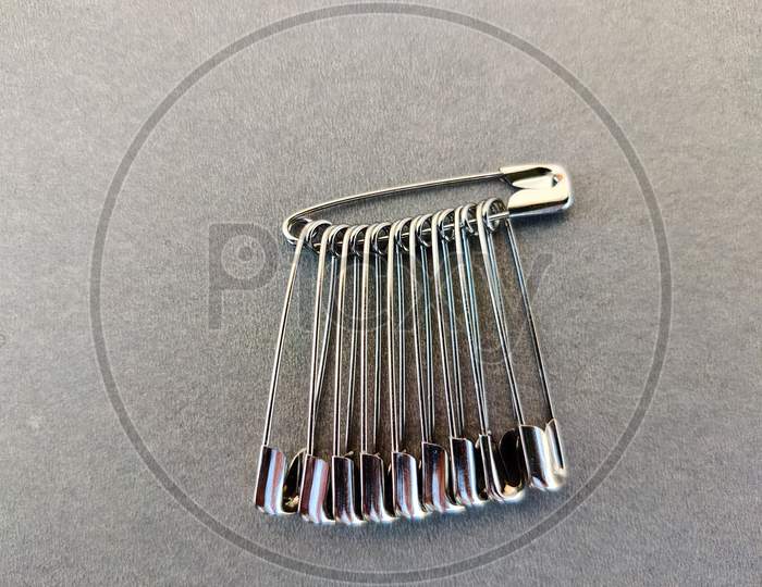 Set Of Safety Pins. Isolated On Grey Background.