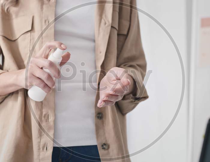 Girl Using Hand Antiseptic At Work. Woman Using Hand Sanitizer At Creative Office. Hands Close Up. Medical Protection, Sanitizer, Corona Virus Concept. Shot On Red