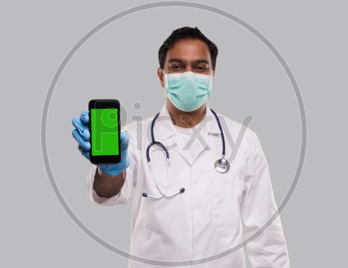 Doctor Showing Phone Wearing Medical Mask And Gloves. Indian Man Doctor Technology Medicine At Home. Phone Green Screen Close Up Isolated