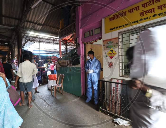 A health worker in personal protective equipment (PPE) waits to collect swab sample from people during a rapid antigen testing campaign for the coronavirus disease (COVID-19), at a vegetable market in Mumbai, India, November 21, 2020.