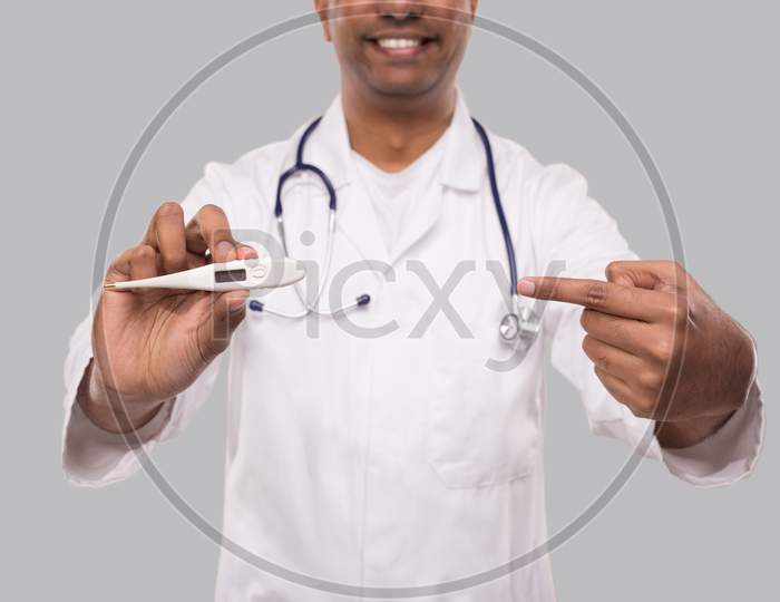 Doctor Pointing At Thermometer Isolated. Indian Man Doctor Smiling With Thermometer In Hands. Healthy Life, Doctor, Virus Concept