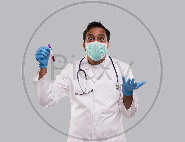 Doctor Surprised Holding Blood Tube Analysis Wearing Medical Mask And Gloves. Indian Man Doctor Science, Medical Concept. Isolated.