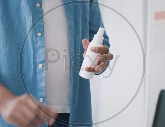 Indian Man Using Hand Antiseptic At Work. Man Using Hand Sanitizer At Creative Office. Hands Close Up. Medical Protection, Sanitizer, Corona Virus Concept. Shot On Red