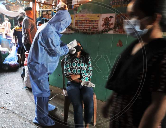 A health worker in personal protective equipment (PPE) collects a swab sample from a woman during a rapid antigen testing campaign for the coronavirus disease (COVID-19), at a vegetable market in Mumbai, India, November 21, 2020.