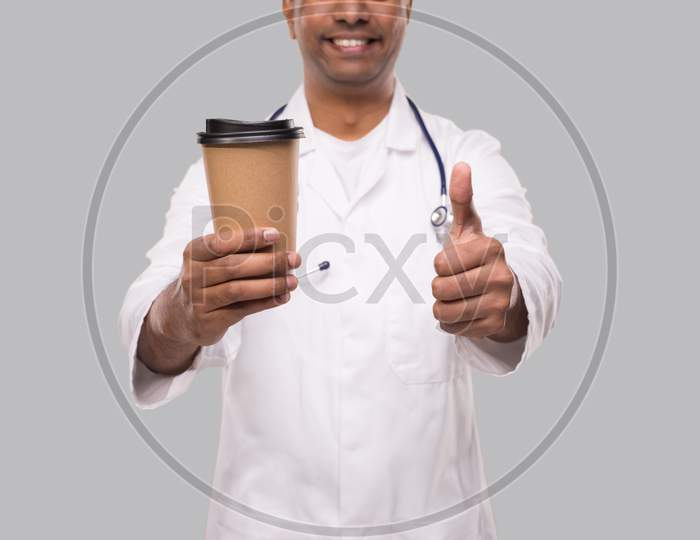 Man Doctor Holding Coffee Take Away Cup Smiling Close Up Isolated. Indian Doctor Holding Coffee To Go Cup.
