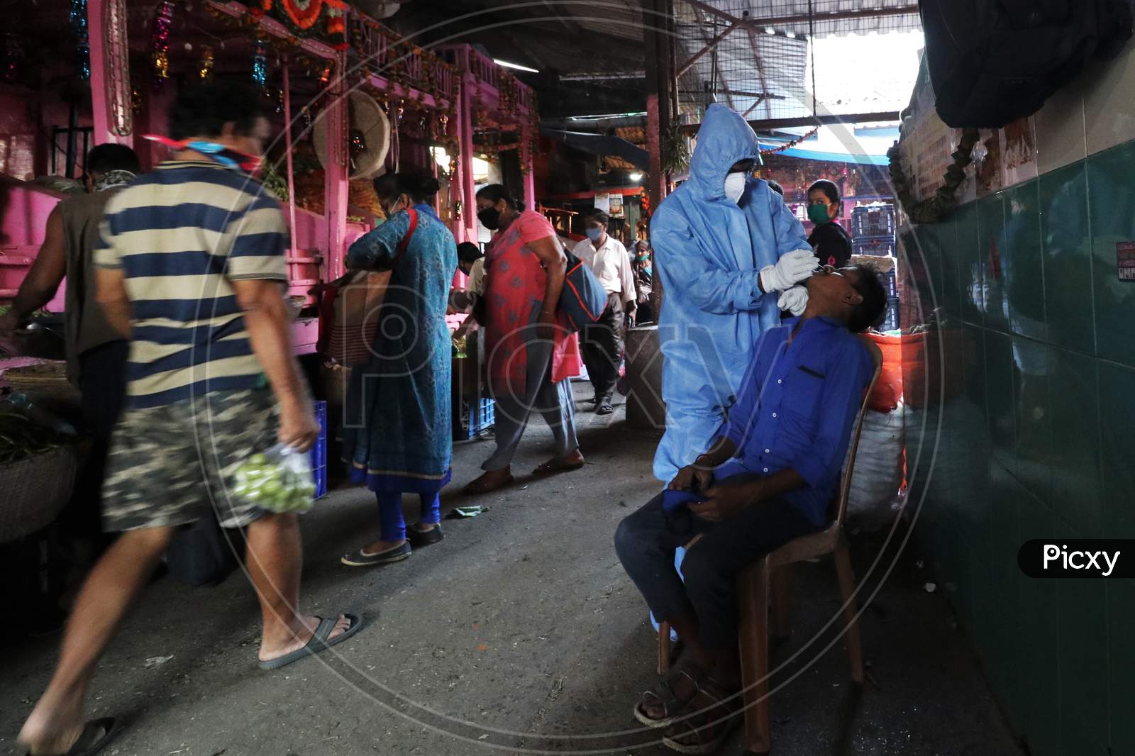 A health worker in personal protective equipment (PPE) collects a swab sample from a man during a rapid antigen testing campaign for the coronavirus disease (COVID-19), at a vegetable market in Mumbai, India, November 21, 2020.