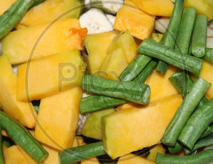 Many Pieces Of Pumpkin, Raw Banana, French Beans, On The Plate With Vegetable Background