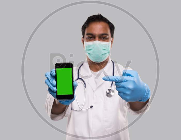 Doctor Pointing At Phone Wearing Medical Mask And Gloves. Indian Man Doctor Technology Medicine At Home. Phone Green Screen Isolated