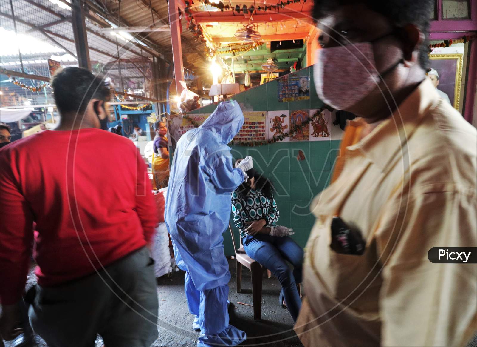 A health worker in personal protective equipment (PPE) collects a swab sample from a woman during a rapid antigen testing campaign for the coronavirus disease (COVID-19), at a vegetable market in Mumbai, India, November 21, 2020.