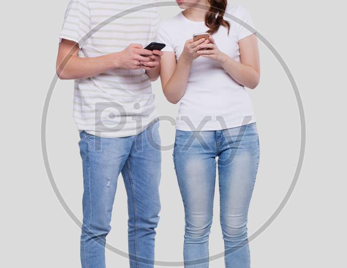 Couple Chatting On Phone. Couple Using Phones Standing Isolated. Couple Shopping Online. Girl Watching In Man Phone.