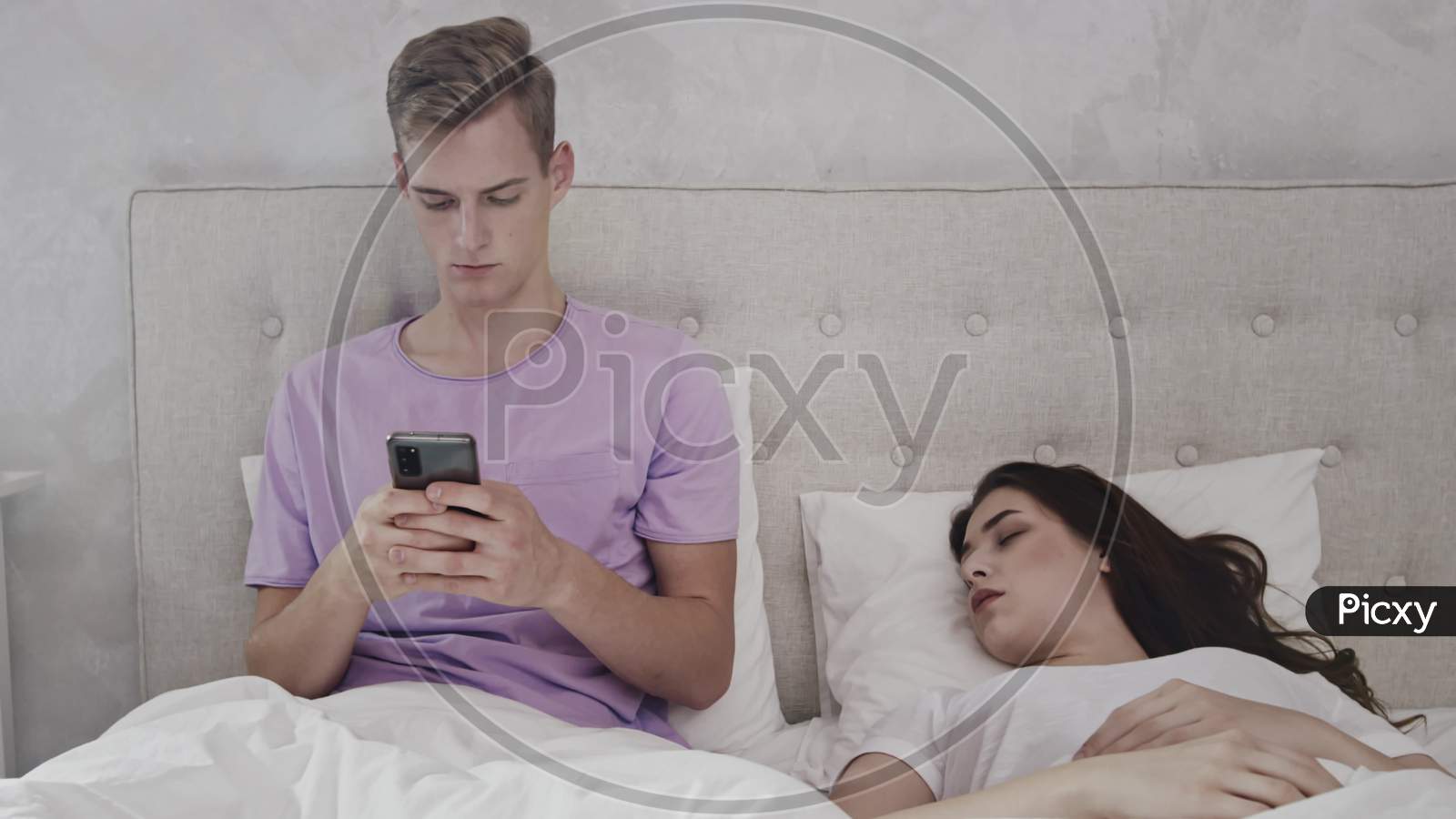 Man Chatting On Phone While Girl Is Sleeping. Man Using Phone In Bed. Girl Sleeping In Bed. Shot On Red