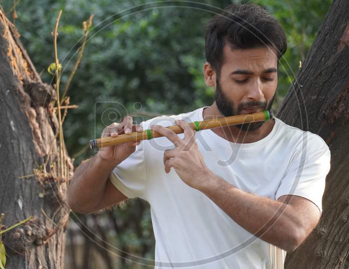 Bansuri Player Playing Music In Sunshine At Park - Indian Flute Player