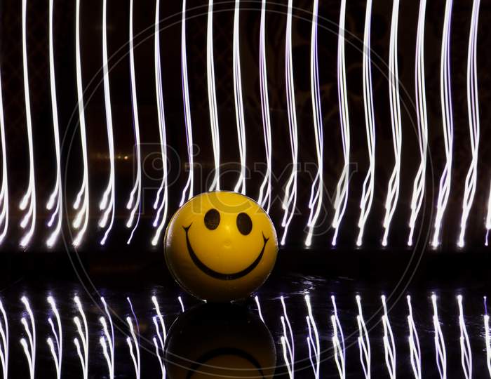 A yellow smiley ball on black background with light stripes on back.
