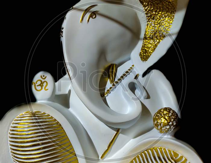 Beautiful Artistic Figurine Of God Ganesha In Gold And White In Black Background.