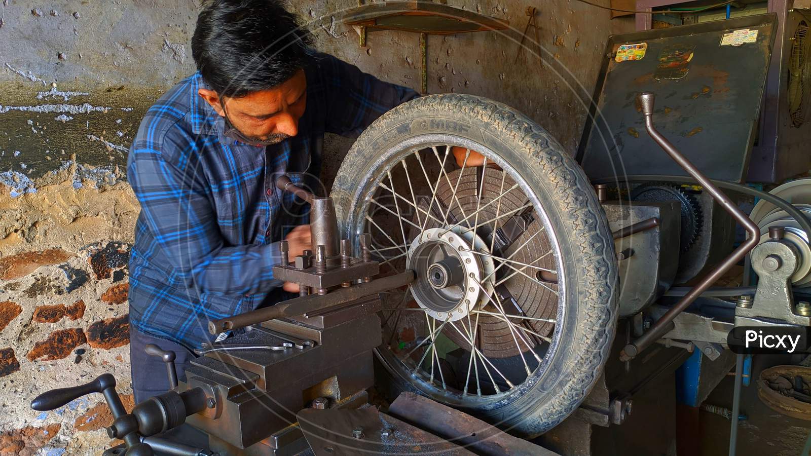 Professional Indian Mechanic Working On Lathe Machine To Repair Bike Tyre.