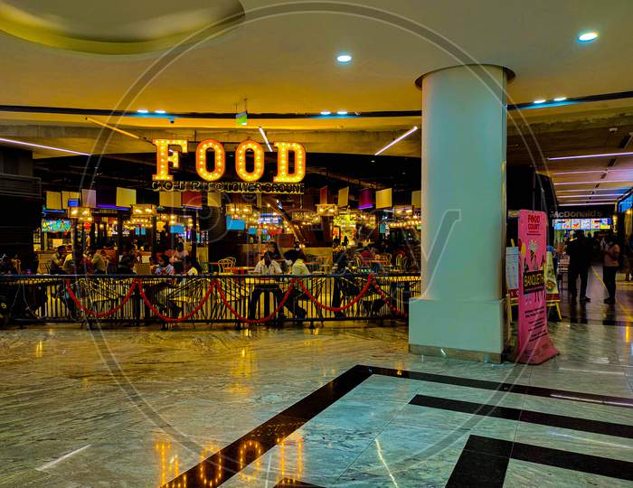 Food Court At A Mall With People Wearing Masks During The Pandemic. Restaurant With Foodies.