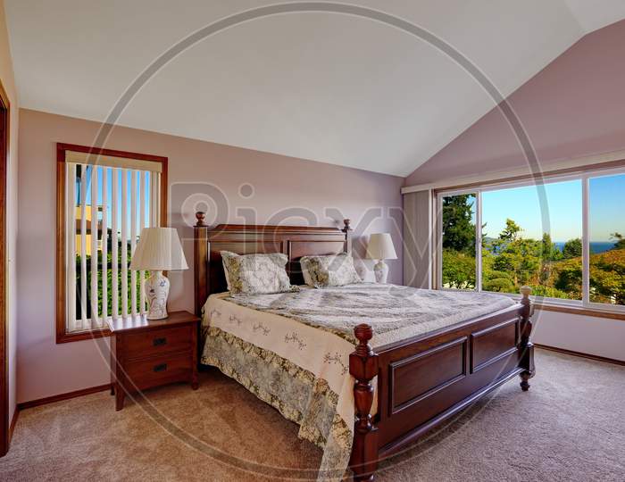 Master Bedroom Interior In Light Pink Color With Scenic Window View. Room With Height Vaulted Ceiling, Carpet Floor And Carved Wooden Furniture Set