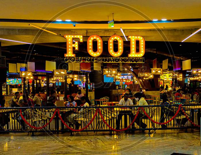 Food Court At A Mall With People Wearing Masks During The Pandemic. Restaurant With Foodies.