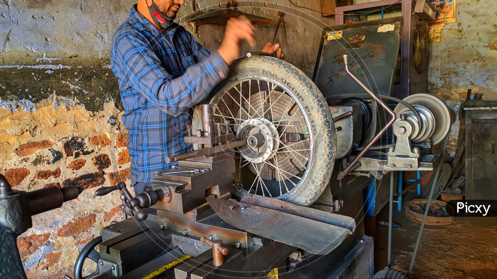 November 2020- Mahroli, Jaipur, India / Professional Indian Mechanic Working On Lathe Machine To Repair Bike Tyre.