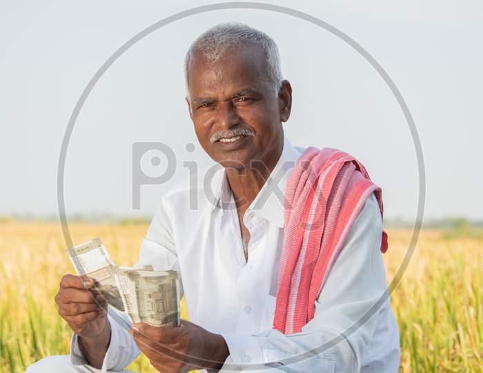 Happy Smiling Indian Farmer Couting Money On Agriculture Field While Looking Camera - Concept Of Good Or Bumper Crop Harvest, Farm Subsidy And Credit