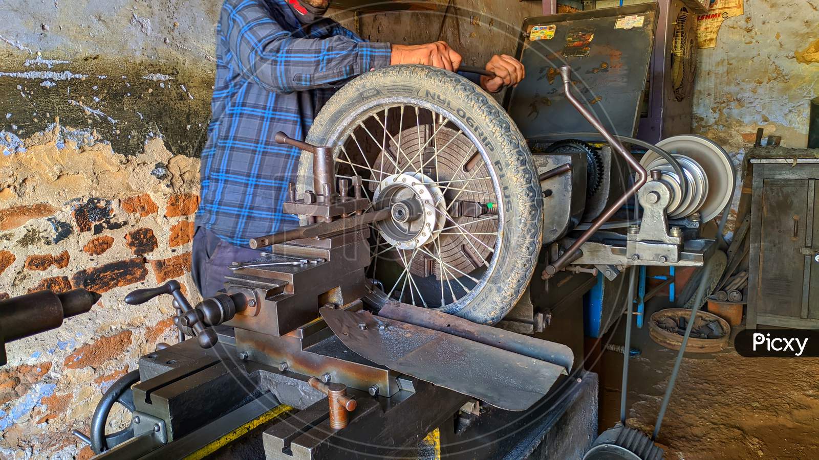 November 2020- Mahroli, Jaipur, India / Professional Indian Mechanic Working On Lathe Machine To Repair Bike Tyre.