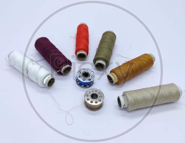 Old Vintage Hand Sewing Machine Colored Thread Coils Or Bobbin On White Background, Sewing Machine Accessories. Selective Focus. Image