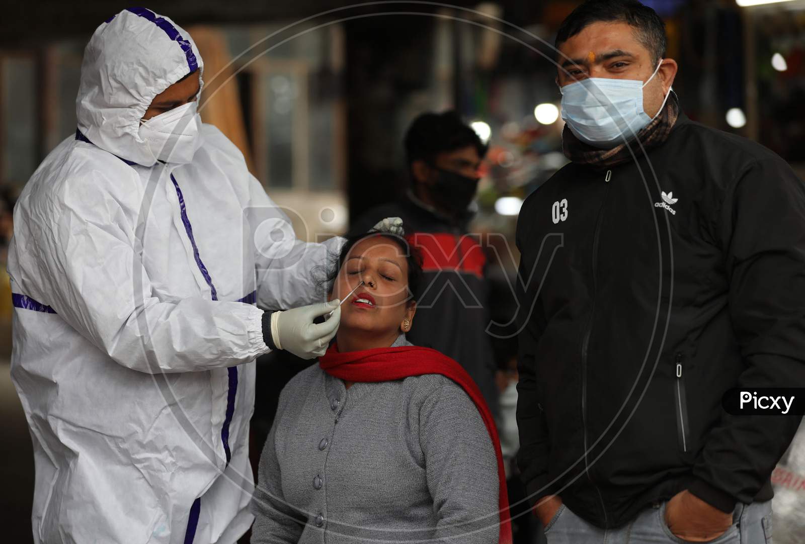 Health worker collects a swab sample for COVID-19 test at Gernal Bus stand in Jammu ,25 November,2020.