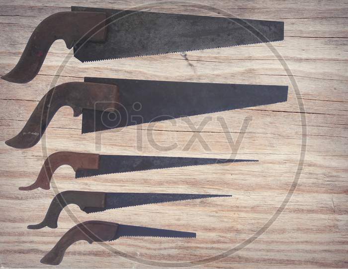Image Of Different Sizes Of Old Hand Saw Isolated On Wooden Background.