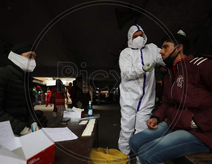 Health worker collects a swab sample for COVID-19 test at Gernal Bus stand in Jammu ,25 November,2020.